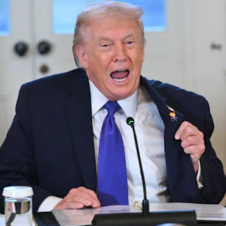 Donald Trump, sitting, speaks vehemently with wide-open mouth