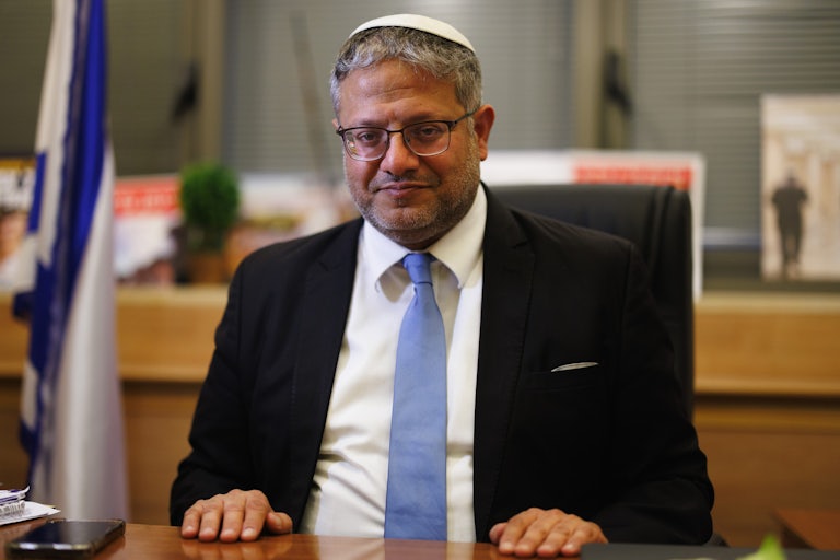 Itamar Ben Gvir, Israel's national security minister, sits at a table. The Israeli flag is in the background.