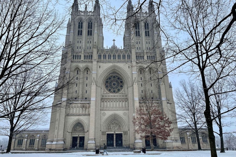 This picture shows Washington National Cathedral in winter, surrounded by bare trees and a thin dusting of snow on the ground.