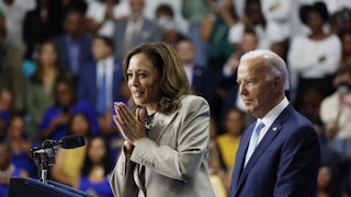 Kamala Harris presses her hands together while smiling, with Joe Biden standing to her right.