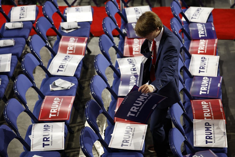 An RNC staffer puts pro-Trump signs on seats