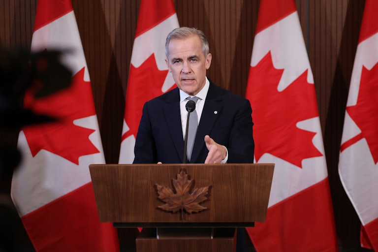 Canadian Prime Minister Mark Carney gestures while speaking at a podium