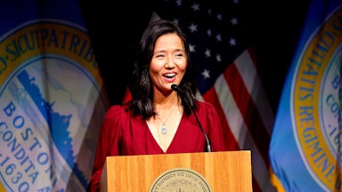 Michelle Wu, dressed in red, speaks at a podium.
