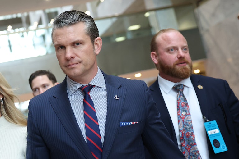 Pete Hegseth walks as others follow him in the back
