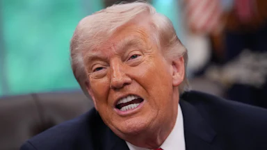Donald Trump speaks while sitting at his desk in the Oval Office