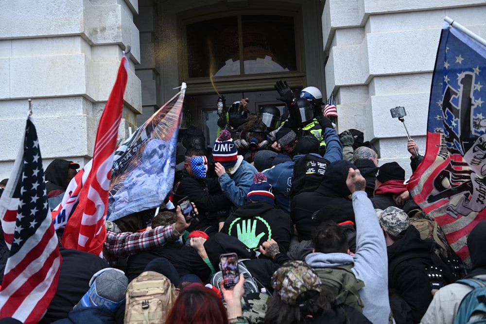 Demonstrators waving flags rush the door of the Capitol building.