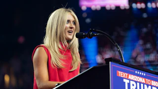 Riley Gaines speaks at a podium with a "Trump-Vance" sign