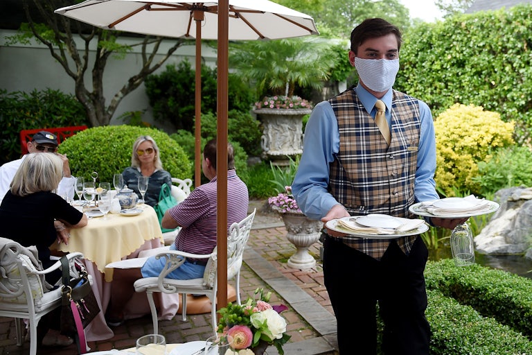 A masked waiter serves a group at an upscale restaurant in Virginia, days into its reopening amid the pandemic.
