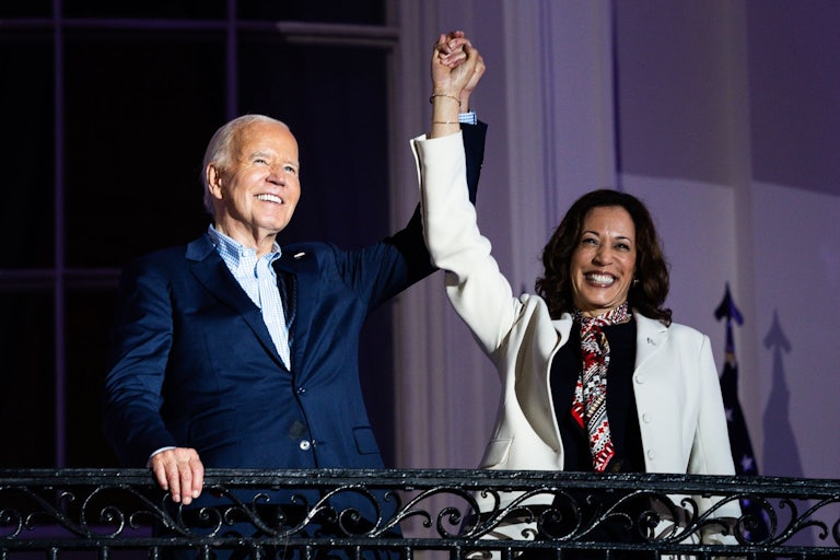 Joe Biden and Kamala Harris raise their clasped hands in the air, as if in victory