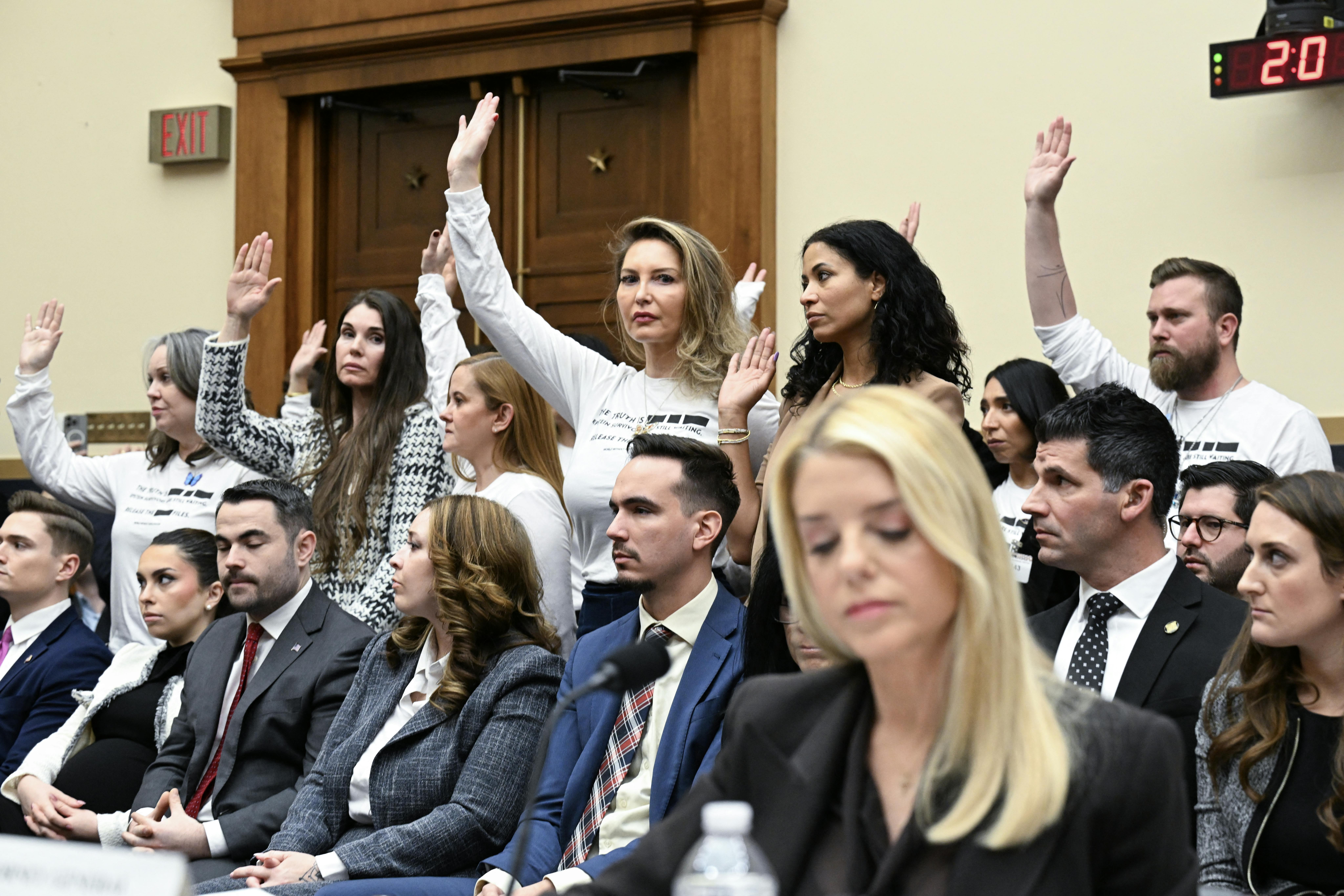 Victims of convicted sex offender Jeffrey Epstein stand during as Attorney General Pam Bondi’s congressional testimony 