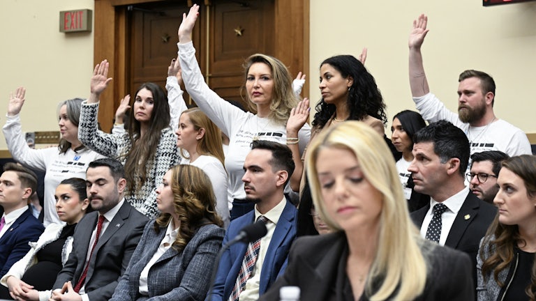 Victims of convicted sex offender Jeffrey Epstein stand during as Attorney General Pam Bondi’s congressional testimony