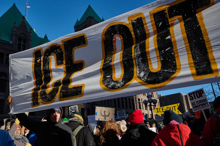 People hold up a banner that says, "ICE out" during a protest in Minneapolis, Minnesota