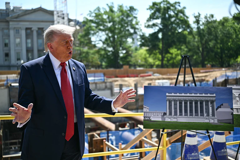 Donald Trump gestures while speaking in front of the White House ballroom construction site