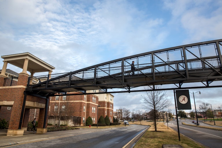 A student walks on a footbridge at the University of Alabama.