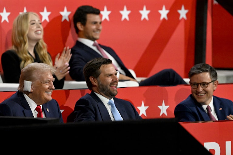 Donald Trump, JD Vance, and Mike Johnson smile while sitting next to each other at the Republican National Convention