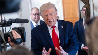 Donald Trump holds his hands out in front of him while speaking to reporters on Air Force One