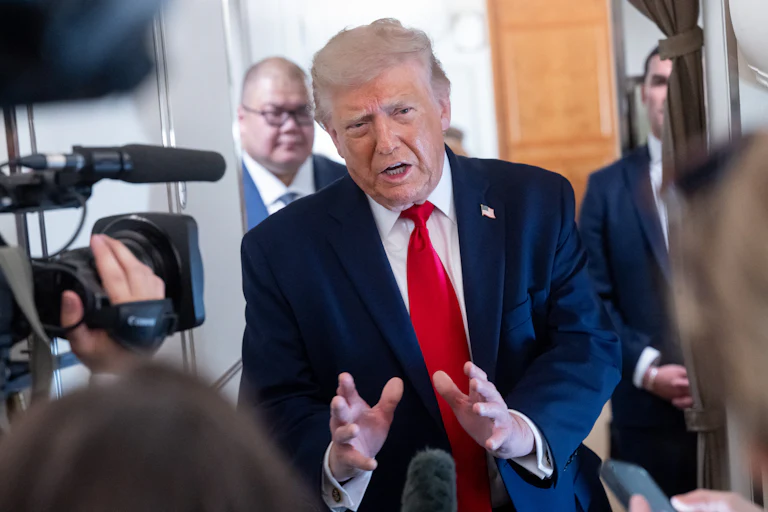 Donald Trump holds his hands out in front of him while speaking to reporters on Air Force One