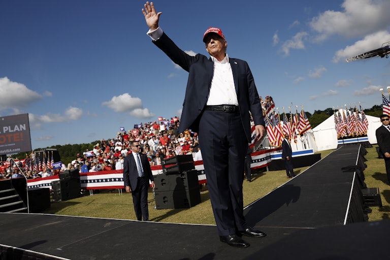 Donald Trump waves to a crowd of followers outdoors