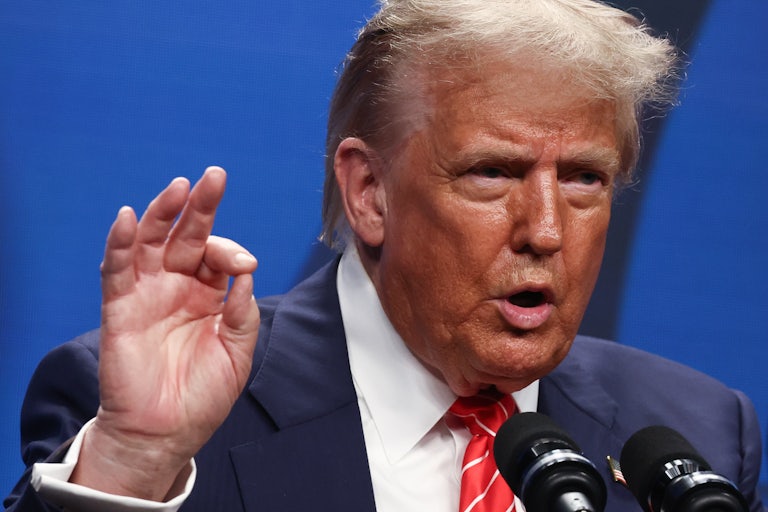 Donald Trump gestures while speaking into microphones