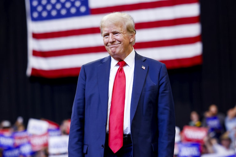 Donald Trump smiles in front of a U.S. flag