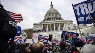 Protesters waving Trump 2020 flags, mob in front of the Capitol building.