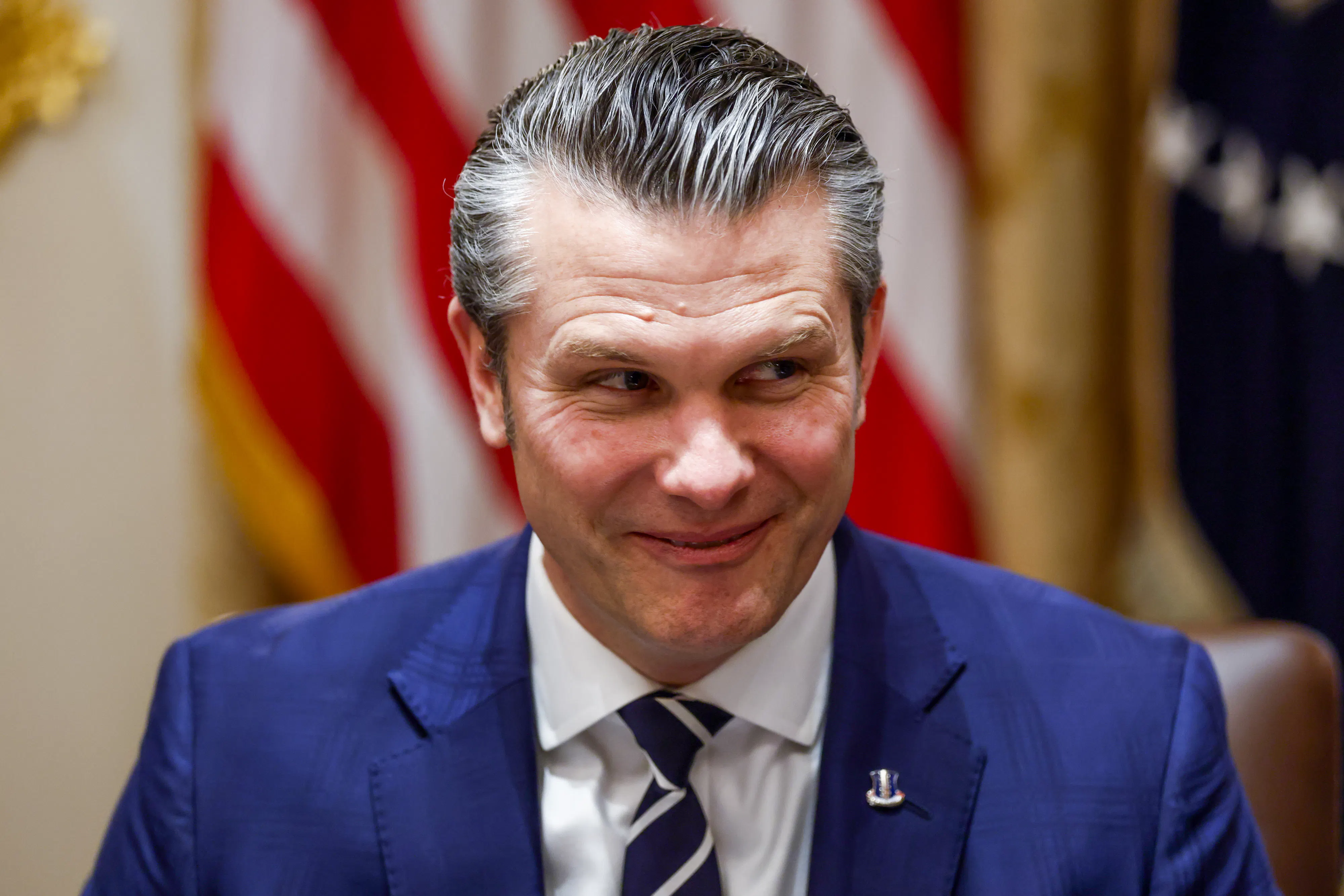 Pete Hegseth looks sideways while grinning