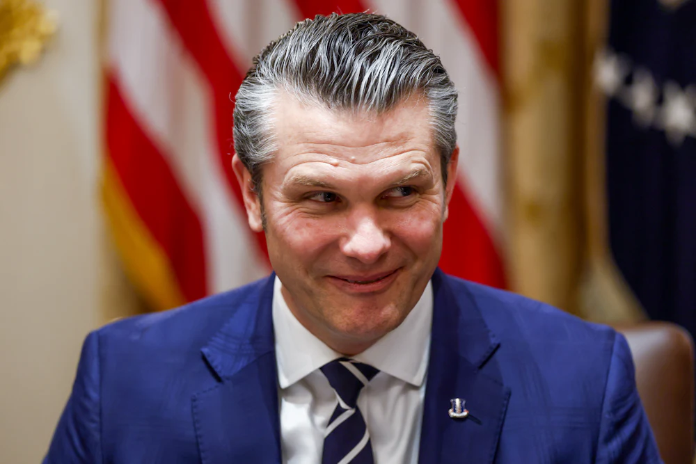Pete Hegseth looks sideways while grinning