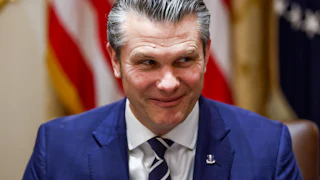 Pete Hegseth looks sideways while grinning