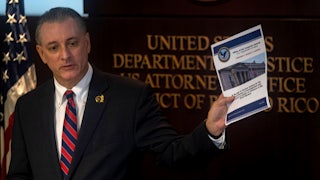 U.S. Attorney for the District of Puerto Rico, W Stephen Muldrow, speaks and holds up a piece of paper in his hand.