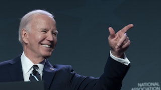 Joe Biden points off camera and smiles.