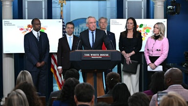 Health Secretary Robert F. Kennedy Jr speaks at the podium in the White House press briefing room. He is flanked by Ben Carson, Marty Makary, Mehmet Oz, Brooke Rollins, and Karoline Leavitt