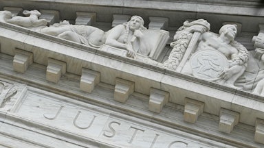 The word “Justice” is seen on the rear side of the U.S. Supreme Court.