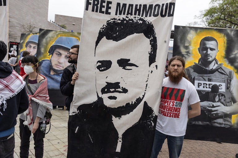 Protesters hold a large banner with Mahmoud Khalil's photo and the words "Free Mahmoud." Others in the background hold up banner photos of killed Palestinian journalists.