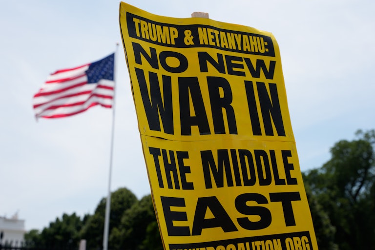 A person holds a sign that says, "Trump & Netanyahu, no new war in the Middle East" at a protest outside the White House