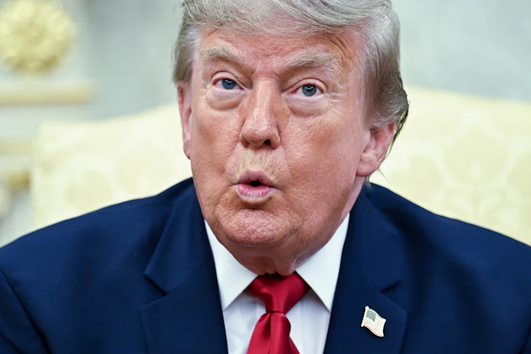 Donald Trump puckers his lips while speaking in the Oval Office.