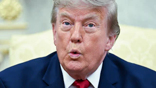 Donald Trump puckers his lips while speaking in the Oval Office.
