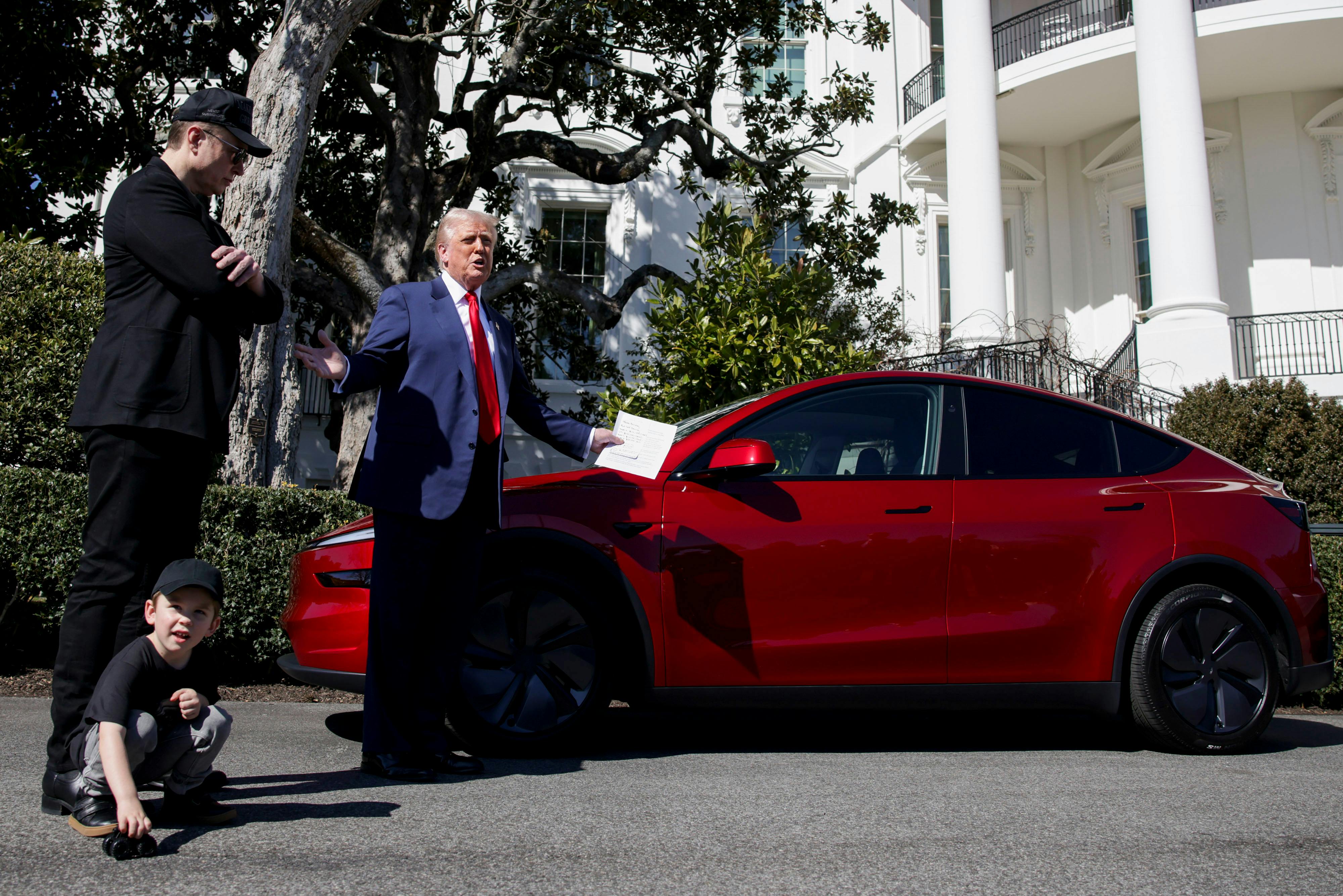 Elon Musk stands next to President Donald Trump both looking at a red Tesla Model S vehicle on the South Lawn of the White House in Washington, DC, US, on Tuesday, March 11, 2025. 
