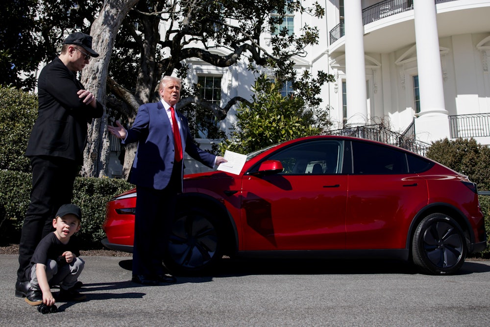 Elon Musk stands next to President Donald Trump both looking at a red Tesla Model S vehicle on the South Lawn of the White House in Washington, DC, US, on Tuesday, March 11, 2025.