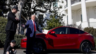 Elon Musk stands next to President Donald Trump both looking at a red Tesla Model S vehicle on the South Lawn of the White House in Washington, DC, US, on Tuesday, March 11, 2025.