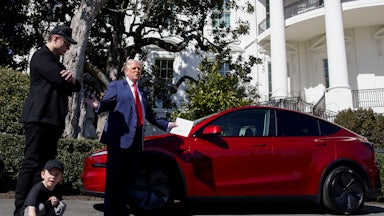 Elon Musk stands next to President Donald Trump both looking at a red Tesla Model S vehicle on the South Lawn of the White House in Washington, DC, US, on Tuesday, March 11, 2025.