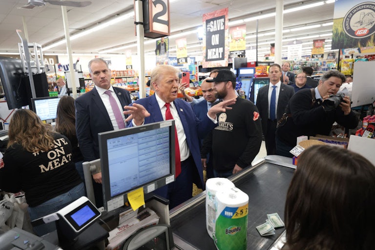 Trump stands amid numerous other people in front of a checkout counter in a grocery store.