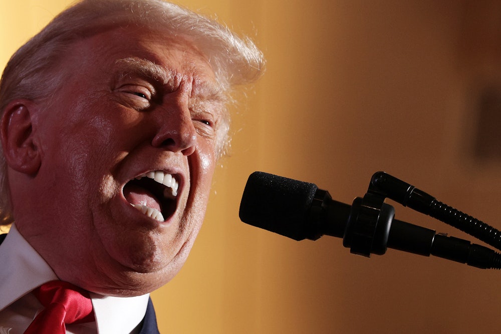 Donald Trump yells into a microphone with wide open mouth