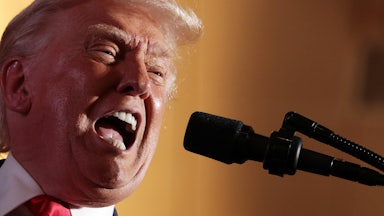 Donald Trump yells into a microphone with wide open mouth