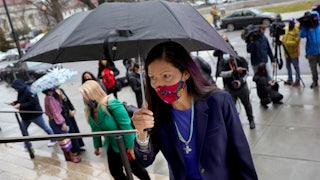 Deb Haaland walks up steps holding an umbrella.