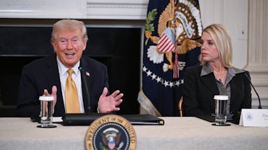 Donald Trump gestures and speaks while sitting next to Attorney General Pam Bondi at a table
