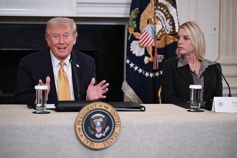 Donald Trump gestures and speaks while sitting next to Attorney General Pam Bondi at a table