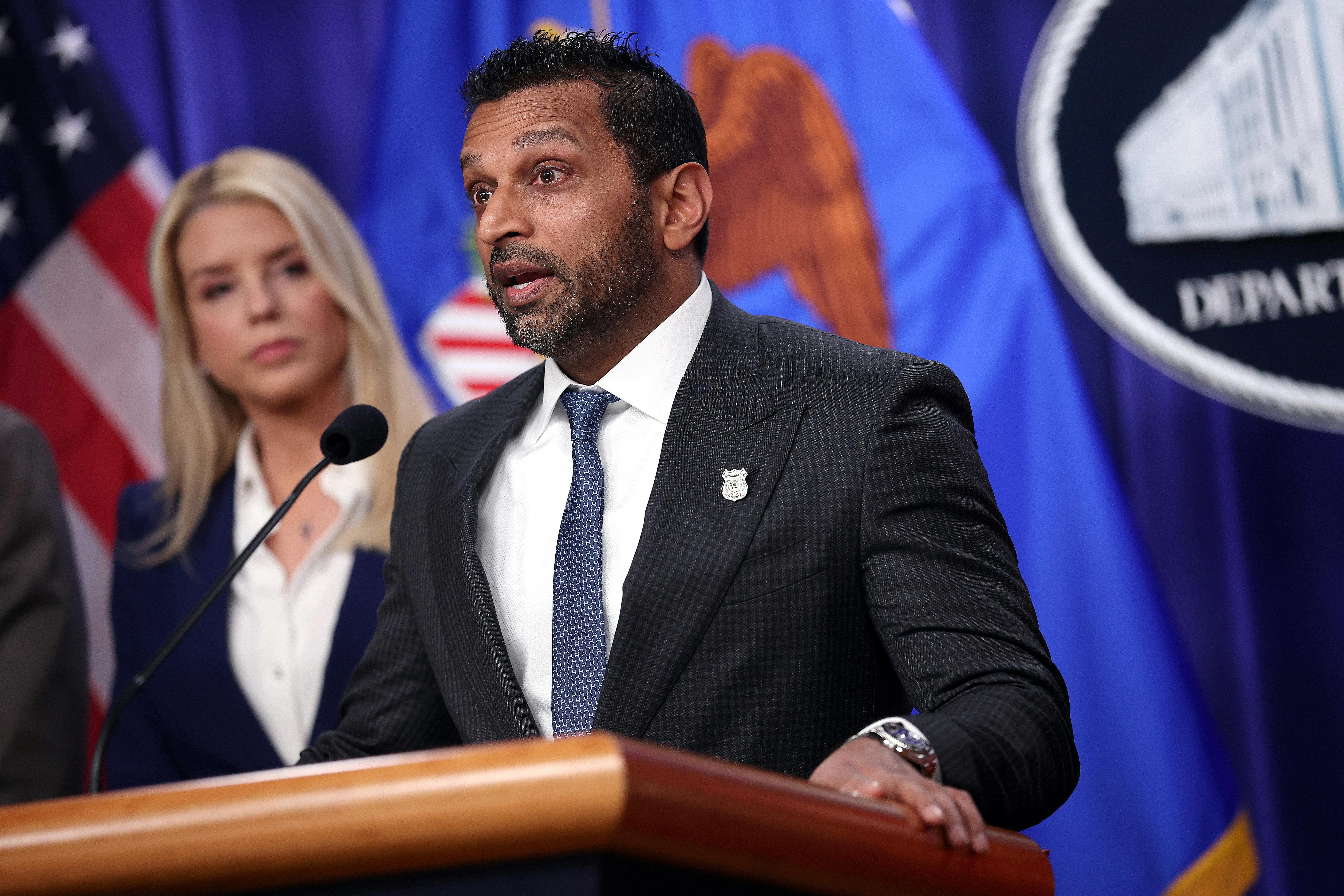 Kash Patel speaks at a podium while Attorney General Pam Bondi stands behind him.