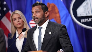 Kash Patel speaks at a podium while Attorney General Pam Bondi stands behind him.