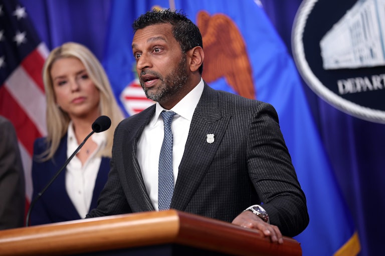 Kash Patel speaks at a podium while Attorney General Pam Bondi stands behind him.