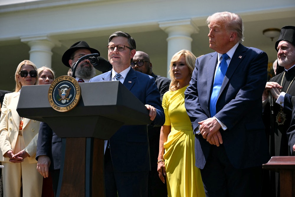President Donald Trump listens to House Speaker Mike Johnson speak during a National Day of Prayer event in the Rose Garden of the White House on May 1, 2025.